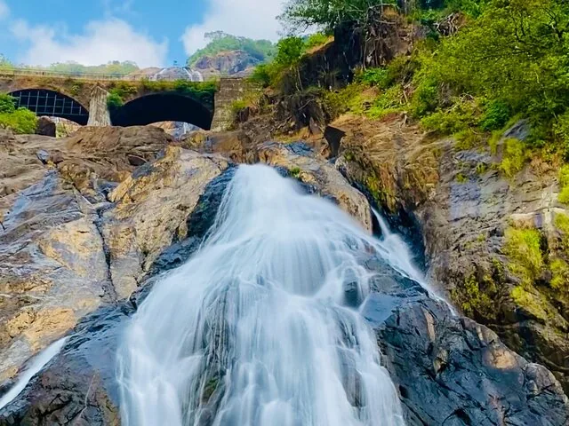 Gros plan sur l'eau tumultueuse des chutes de Dudhsagar, avec un pont au-dessus