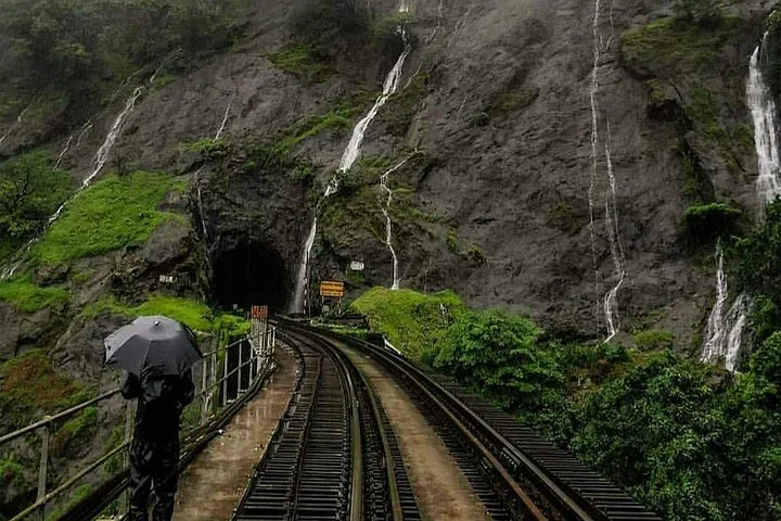 Persona con paraguas caminando sobre las vías del tren cerca de un túnel