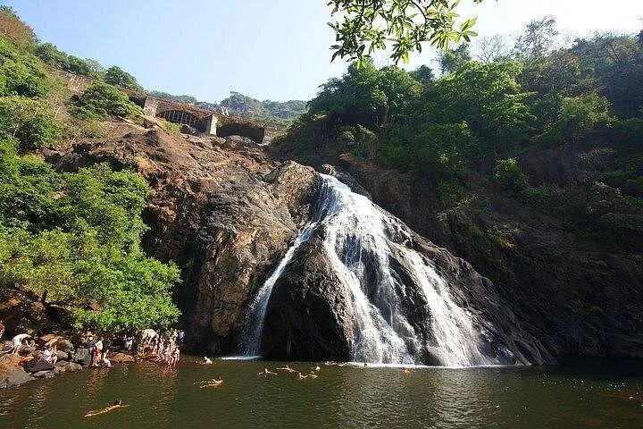 People swimming and relaxing at the base of Dudhsagar Falls