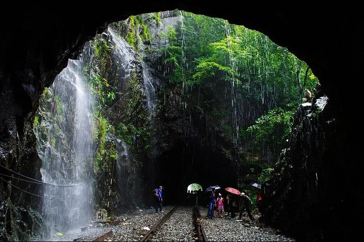 Personnes avec des parapluies explorant des voies ferrées dans un tunnel